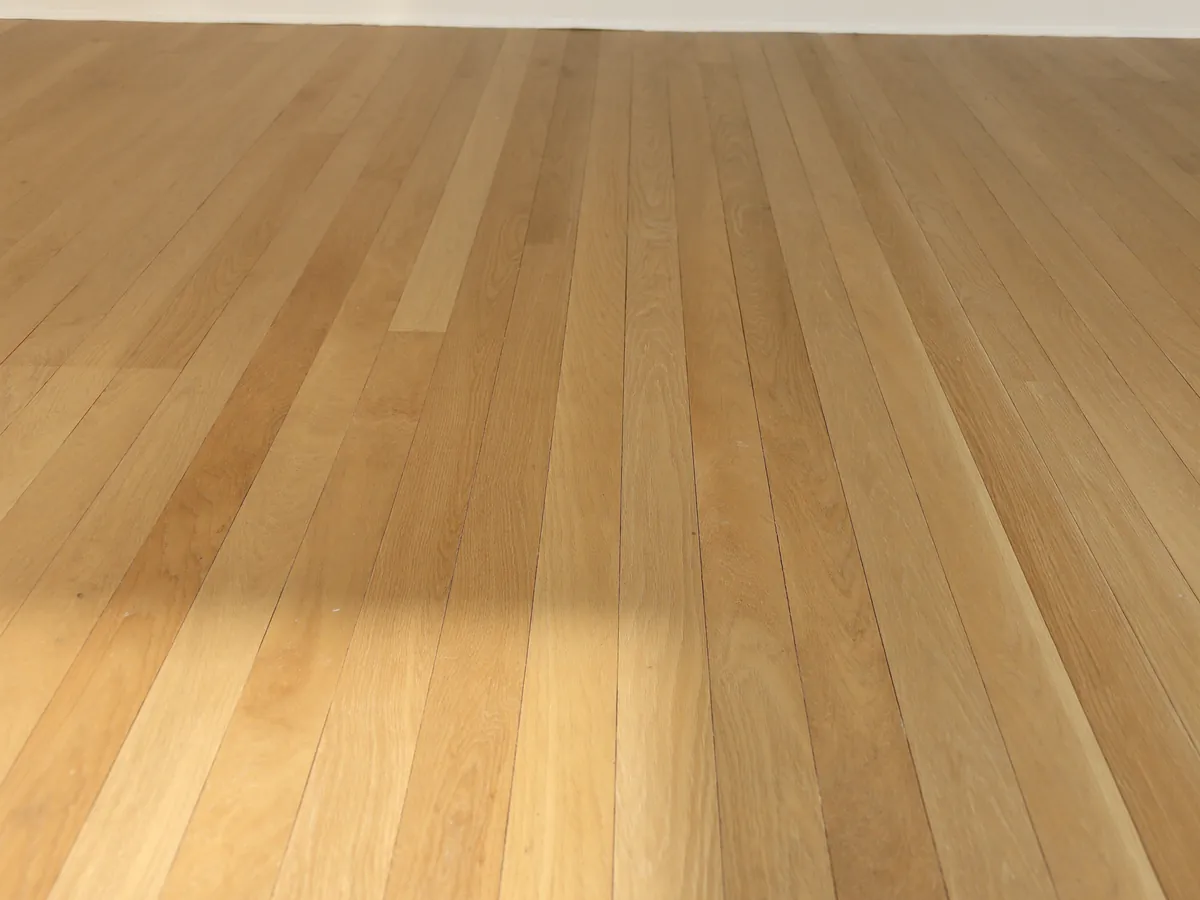 Solid white oak hardwood flooring running across an empty room in natural daylight